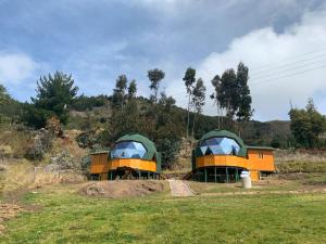 CuítivaGlamping Los Balcones的田野上的两个绿色和橙色帐篷