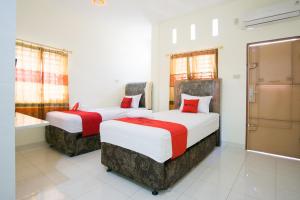 先达RedDoorz @ Pematangsiantar 2的红色和白色的酒店客房内的两张床