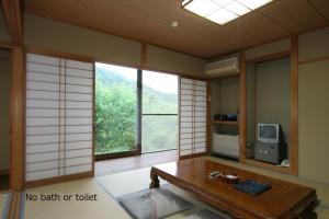 南木曾町东光味噌日式旅馆的客房设有桌子、电视和窗户。