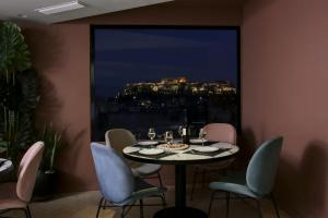雅典艾弗瑞派德酒店的一间带桌椅和大窗户的用餐室