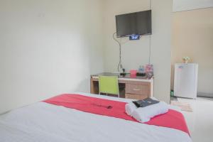 占碑市RedDoorz Syariah near Jamtos Jambi 2的一间卧室配有一张带书桌的床和一台电视。