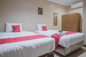 占碑市RedDoorz Syariah near Jamtos Jambi 2的配有红色和白色床单的客房内的两张床