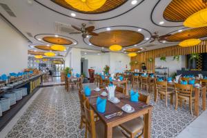 会安Fivitel Hoi An Hotel的餐厅设有木桌、椅子和黄色的灯光