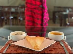 NarokLorian safari camp limited的桌上的两杯咖啡和一块面包