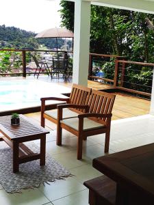 伊利亚贝拉SOL&MAR Suítes Ilhabela的庭院设有2张长椅、1张桌子和1个游泳池