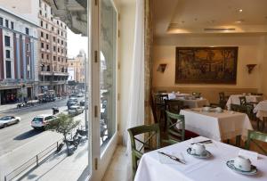 马德里大西洋酒店的一间设有桌子并享有街道景色的餐厅