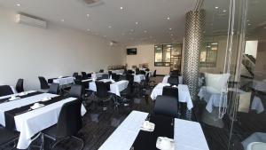 纳卡拉Indico Executivo Hotel的用餐室配有白色桌子和黑色椅子