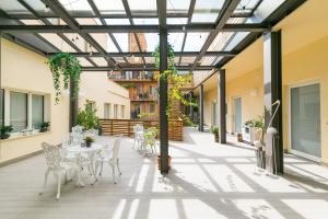 罗马Demetra Eco Guest House的庭院设有白色的桌椅和玻璃天花板。