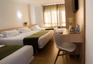 米尼奥Hotel Crisol de las Rías的酒店客房设有三张床、一张桌子和一把椅子。