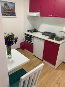 雅戈丁那La Apartamento Centroom的一间设有红色橱柜和花瓶桌子的小厨房
