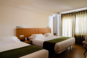 米尼奥Hotel Crisol de las Rías的酒店客房,配有两张床和椅子