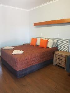 滕南特克里克Safari Lodge Motel的橙色和白色枕头的宿舍间内的一张床位