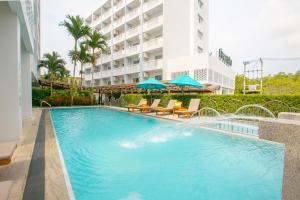 普吉镇普吉岛苏伦套房酒店的一座带椅子和遮阳伞的游泳池位于一座建筑旁边