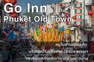 普吉镇Go Inn Phuket old Town的一群人沿着一条挂着旗帜的街道走着