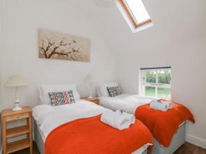 希莱拉The Old White Cottage的一间带两张橙色毯子床铺的卧室