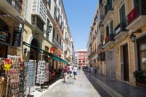 马拉加Hola Málaga Centro Histórico的一群人沿着街道走着,街道上有许多建筑