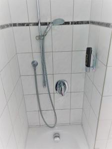 巴特嫩多夫A&M Hotel Barsinghausen的浴室内带软管的淋浴