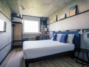 卡斯特尔德费尔斯巴塞罗那卡斯特尔德菲尔宜必思酒店的一间卧室配有一张带蓝白色枕头的大床