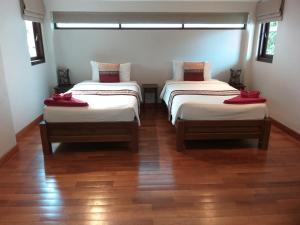 小通奈潘Koh Phangan Pavilions Serviced Apartments的铺有木地板的客房内的两张床