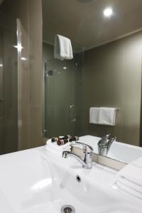 奥克兰机场庄园旅馆的浴室设有白色水槽和镜子