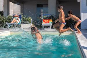 卡普多兰多Terraces d'Orlando - Family Apartments with Sea View and Pool的一群男孩在游泳池玩耍