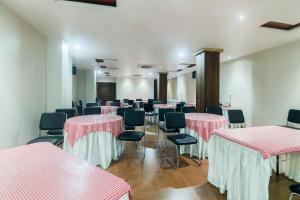 焦尔哈德Hotel Gulmohar Grand的配有粉色和白色桌椅的房间