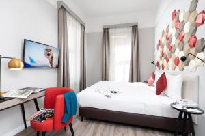 布达佩斯Three Corners Hotel Art的一间卧室配有一张床、一张桌子和一把红色椅子