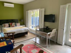 斯泰伦博斯Frida’s Place - Quiet in Stellenbosch Central的一间卧室配有一张床、一张桌子和一台电视。