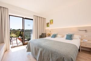 波多佩特罗Hotel Playa Mondrago的酒店客房设有一张大床和一个阳台。