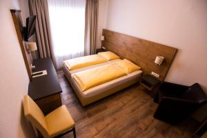格伦察-维伦ZUM ZIEL Hotel & Restaurant Grenzach-Wyhlen bei Basel的一间小卧室,配有一张床和一把椅子