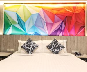 曼谷叻差达迷你R酒店的色彩缤纷的墙壁前的一张带枕头的床