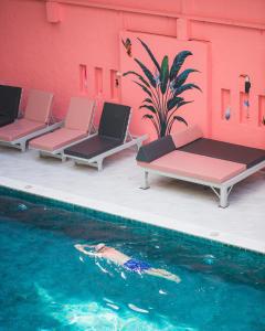 芭堤雅市中心森德雷度假酒店的一座带三把躺椅的游泳池位于大楼旁