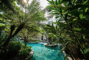 曼谷Hua Chang Heritage Hotel的一座棕榈树游泳池和一座建筑