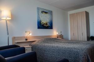 比伦布伦海滨酒店的卧室配有一张床,墙上挂有绘画作品