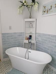 北安普敦Ambles的浴室铺有蓝色瓷砖,配有白色浴缸。