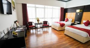 麦纳麦朱菲尔门酒店 的酒店客房带两张床和一张桌子以及椅子。