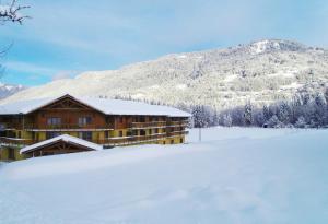莫里永Vacancéole - Résidence Grand Massif的雪中小屋,背景是一座山