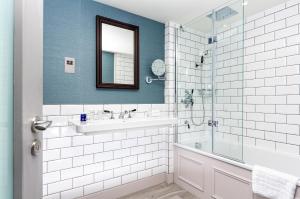 爱丁堡InterContinental Hotels - Edinburgh The George, an IHG Hotel的一间带水槽和玻璃淋浴的浴室