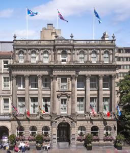 爱丁堡InterContinental Edinburgh The George, an IHG Hotel的前面有旗帜的大型石头建筑