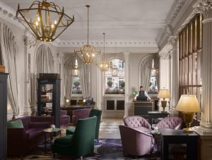 爱丁堡InterContinental Edinburgh The George, an IHG Hotel的大厅里有一个紫色椅子和一个女人站在房间里