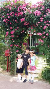 庆州金庆州贝鲁斯玫瑰公寓的两个孩子站在一丛粉红色玫瑰下