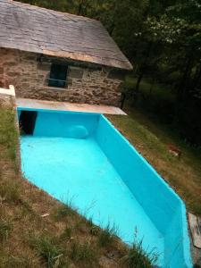 帕拉斯德丽Molino de Louzao的一座蓝色的游泳池,毗邻一座石头房子
