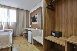 卡里亚西卡Nobile Inn Meridional Cariacica的酒店客房配有一张床、一个水槽和一张书桌