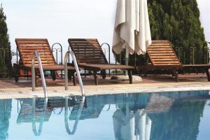 埃拉托克里昂神话酒店的一组椅子和遮阳伞,位于游泳池旁