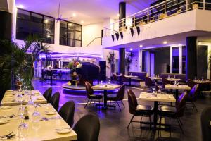 拉古洼Doulos Phos The Ship Hotel的餐厅配有白色的桌椅和紫色的灯光