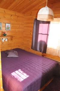 KosulaSuvaksen Helmi的木制客房的紫色床,设有窗户