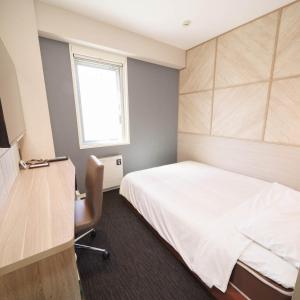 高山高山飞驒超级酒店的一间卧室配有一张床、一张书桌和一个窗户。