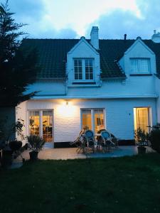 NieuwmunsterZee Vakantievilla Begijnhof 5 De Haan的院子里的白色房子,配有椅子和桌子