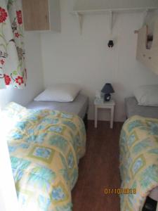 GarlanLes Mobile home de KERROYAL的客房设有两张床和一张带台灯的桌子。