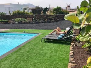 拉哈雷斯Turquesa 2 Fuerteventura的两人躺在游泳池旁的草坪椅上